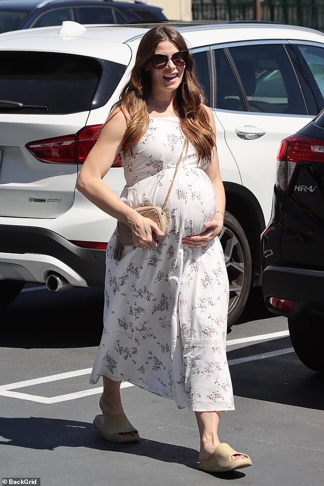 Ashley Greene cradles her baby bump wearing a flower print maternity