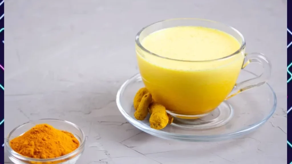 A glass cup filled with yellow liquid ( a mixture of milk and turmeric powder) next to a bowl of turmeric