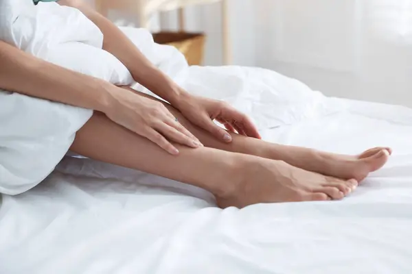 Person experiencing restless legs at night at the edge of a bed